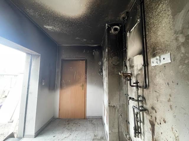 Verrußter Hausflur nach einem Brand mit geschwärzter Decke und Wand