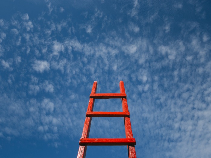 Rote Leiter vor blauem Himmel als Sinnbild für berufliche Entwicklung