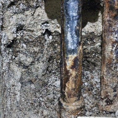 Freigelegte, korrodierte Steigleitung im aufgestemmten Mauerwerk