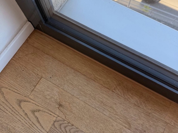 Aufgequollenes Parkett an einer Balkontür als Folge eines Wasserschadens